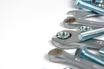 several open-end metal wrenches for working with bolts. Close-up on a white background. Silver metal fixing bolts and nuts. Copy space