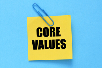CORE VALUES words written on a yellow sheet of paper and a blue background.