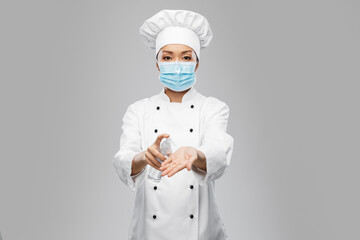 cooking, safety and health concept - female chef in protective medical mask and toque applying hand...