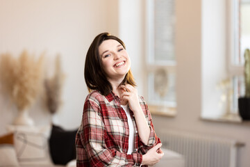 Happy young woman smiling at the camera at home, successful female with positive emotions