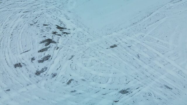 Flying over a snowy field. Straw bales are stacked. Traces of agricultural tillage are visible under the snow. Aerial photography.