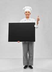 cooking, advertisement and people concept - happy smiling female chef holding big black chalkboard over grey background