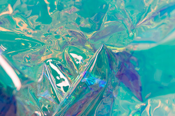 Turquoise blurred holographic background. Wrinkled foil surface. Defocused surreal texture.