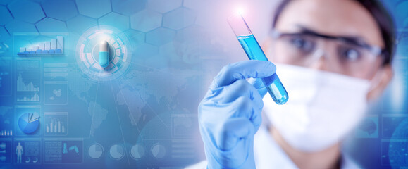 Woman chemist examining a test-tube with blue liquid while working at drugs synthesis in scientific...