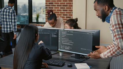 Mixed programers team working on group project on multiple screens showing running code in it...