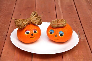 Orange. cheerful round orange with eyes in a basket. on a wooden background. carving for oranges and fruits
