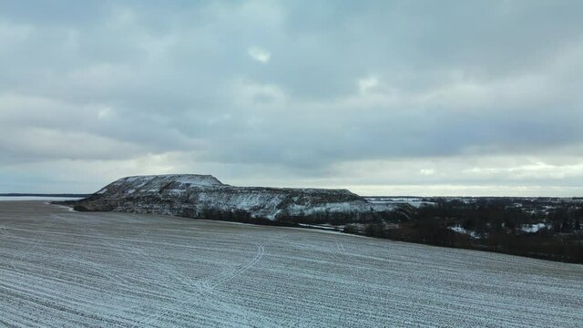 Flying over a snowy field. The city dump is visible, covered with snow. Mothballed waste landfill. Aerial photography.