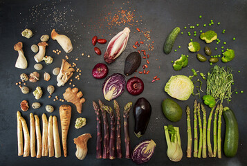 Plant based modern flat lay big set collection white red purple green vegetables on black background. Asparagus, red cabbage, avocado, eggplants, onion. Healthy food concept. Overhead. Top view.