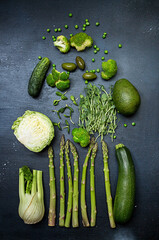 Set collection spring summer seasonal vegetables asparagus zucchini cabbage avocado etc. Modern flat lay green on black background. Overhead.