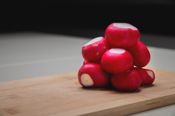 Close-up of partially peeled radishes in a pile on a wooden board. Vegetarian salad ingredient. Vegan food
