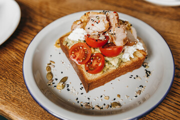 Avocado toast with chicken placed on a wooden table.