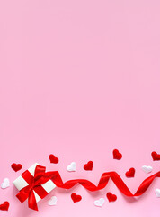 The concept of Valentine's Day. White and red hearts, a gift with a satin ribbon on a pink background. Flat lay, copy space