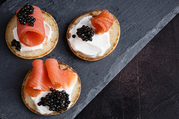 Pancakes with black sturgeon caviar and salmon on a slate