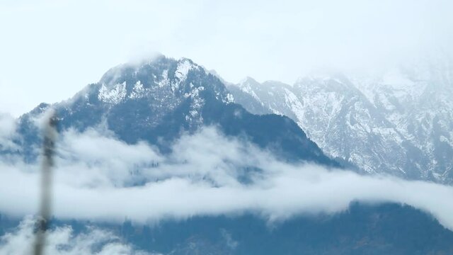 Time lapse of the cloud stream in front of the snow covered mountain peak of the Himalayan mountain range during the snow storm at Manali in Himachal Pradesh, India. Clouds during snow storm timelapse