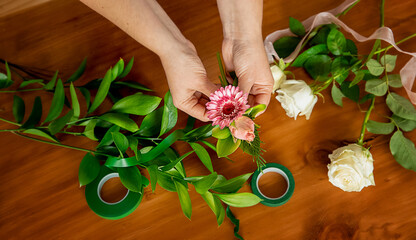 Obraz na płótnie Canvas florist hands holding a fresh flower, making a bouquet or flower arrangement, florist master class or workshop. High quality photo