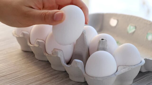 Chicken egg on the table. Easter eggs background. human hand takes one from eggs packed in carton. Close-up shooting