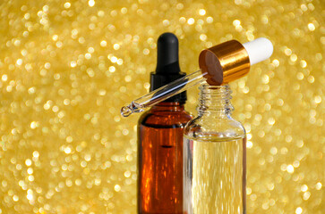 Serum bottles, micellar toner and emulsion on gold glitter background. Cosmetic spa skin care.