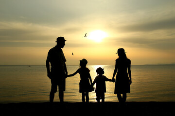 Fototapeta na wymiar family silhouette at sunset by the sea