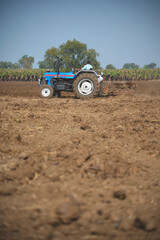 Obraz premium Indian farmer working with tractor in agriculture field.