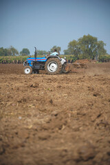 Obraz premium Indian farmer working with tractor in agriculture field.