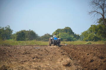 Indian farmer working with tractor in agriculture field.