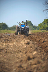 Indian farmer working with tractor in agriculture field.