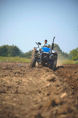 Indian farmer working with tractor in agriculture field.