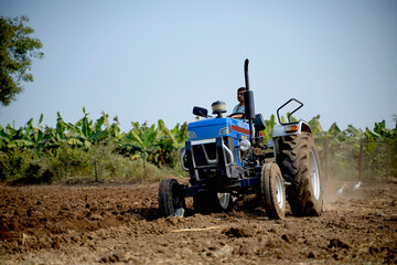 Obraz premium Indian farmer working with tractor in agriculture field.