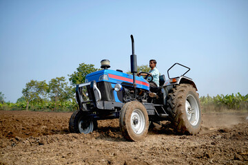 Obraz premium Indian farmer working with tractor in agriculture field.