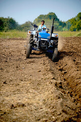 Indian farmer working with tractor in agriculture field.