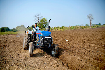 Indian farmer working with tractor in agriculture field.