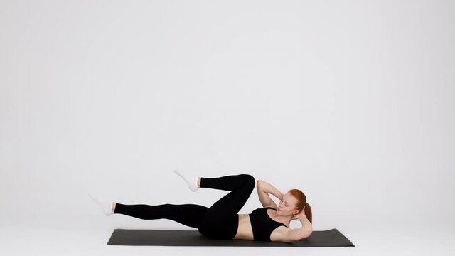 Athletic Female Doing Elbow-To Knee Abs Crunches Exercise While Training In Studio