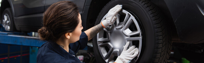 Young mechanic holding disk of car wheel in service, banner.