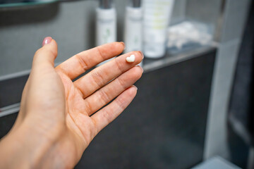 Female hand with cream in the form of a heart on a bath background. Dermatology