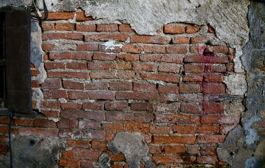 The Old Cracked Wall of a concrete building. A part of the red brick wall was abandoned.