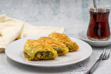 Pistachio baklava (Sobiyet) on stone background. Traditional Turkish cuisine delicacies. Close-up.