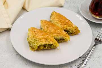 Pistachio baklava (Sobiyet) on stone background. Traditional Turkish cuisine delicacies. Close-up.