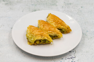 Pistachio baklava (Sobiyet) on stone background. Traditional Turkish cuisine delicacies. Close-up.