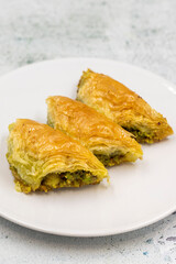 Pistachio baklava (Sobiyet) on stone background. Traditional Turkish cuisine delicacies. Close-up.