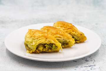 Pistachio baklava (Sobiyet) on stone background. Traditional Turkish cuisine delicacies. Close-up.