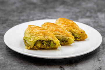 Pistachio baklava (Sobiyet) on dark background. Traditional Turkish cuisine delicacies. Close-up.