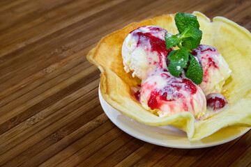 Ice cream balls drizzled with jam on a waffle plate. Close-up, selective focus