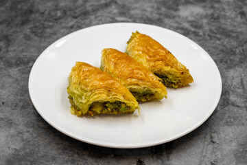 Pistachio baklava (Sobiyet) on dark background. Traditional Turkish cuisine delicacies. Close-up.