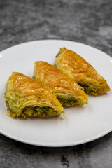 Pistachio baklava (Sobiyet) on dark background. Traditional Turkish cuisine delicacies. Close-up.
