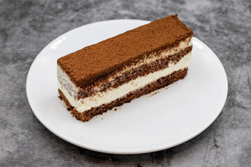 portion tiramisu cake on dark background. Traditional world cuisine delicacies. Close-up.
