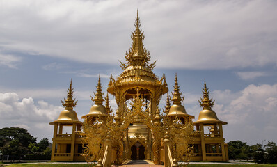 Fototapeta na wymiar Chiang Rai, Thailand - Sep 05, 2020 : Elaborate sculptures of golden pagoda at the famous Wat Rong Khun (White Temple) in Chiang Rai, Thailand. Selective Focus.