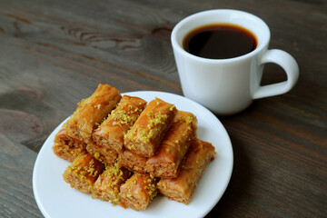 Plate of Pistachio Nuts Baklava Pastries with a Cup of Hot Coffee on Black Wooden Table