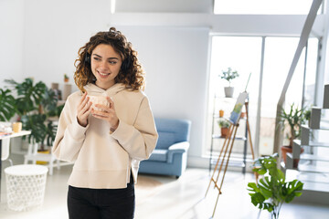 pretty woman works from home with headphones with a cup