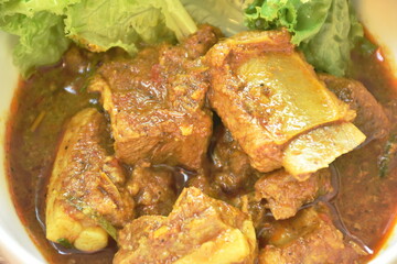 spicy fried pork bone with coconut milk curry on lettuce in bowl