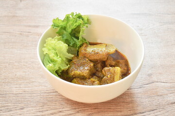 spicy fried pork bone with coconut milk curry on lettuce in bowl